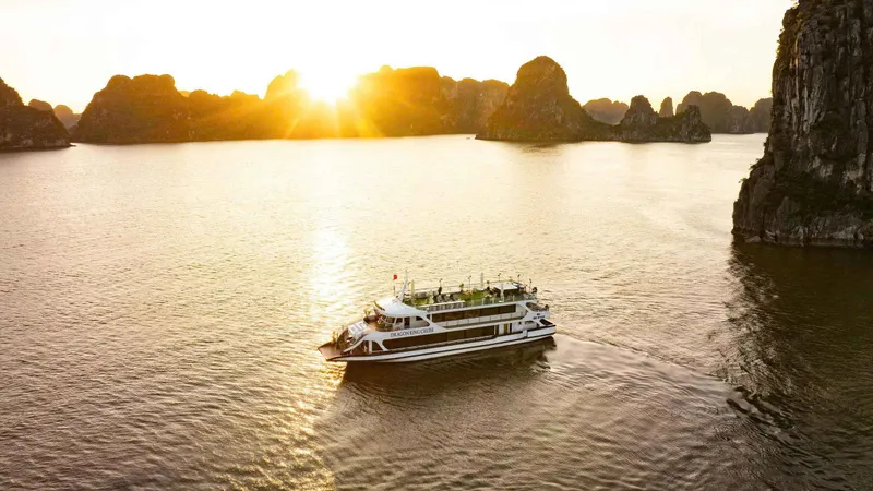Day boat crossing the bay at sunset on a Ha Long Bay junk boat cruise from Hanoi, Vietnam
