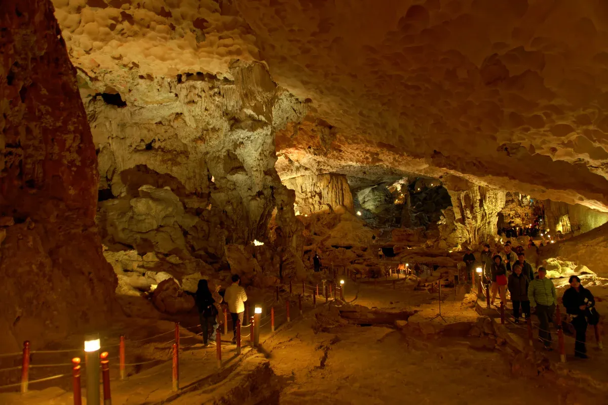Visitors walking inside Sung Sot Cave on a Ha Long Bay junk boat cruise